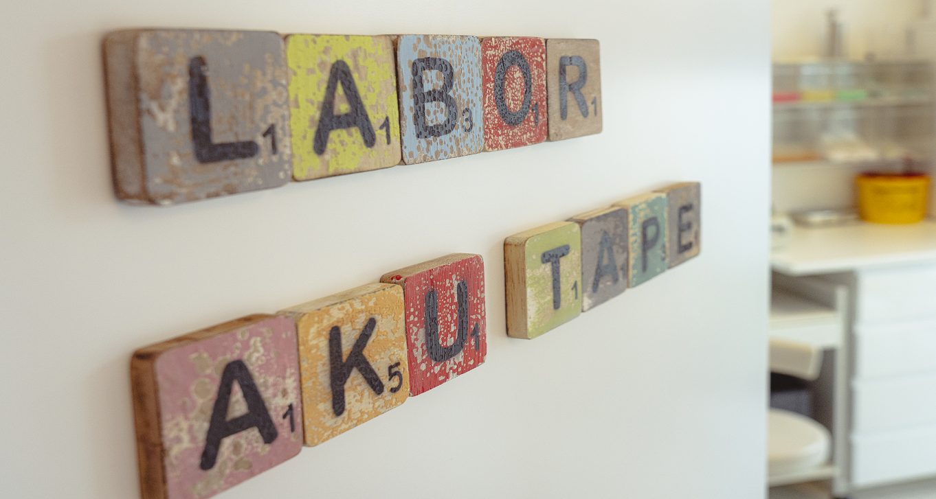 Bunte Holzbuchstaben an der Wand am Labor mit den Worten Labor und Akutape